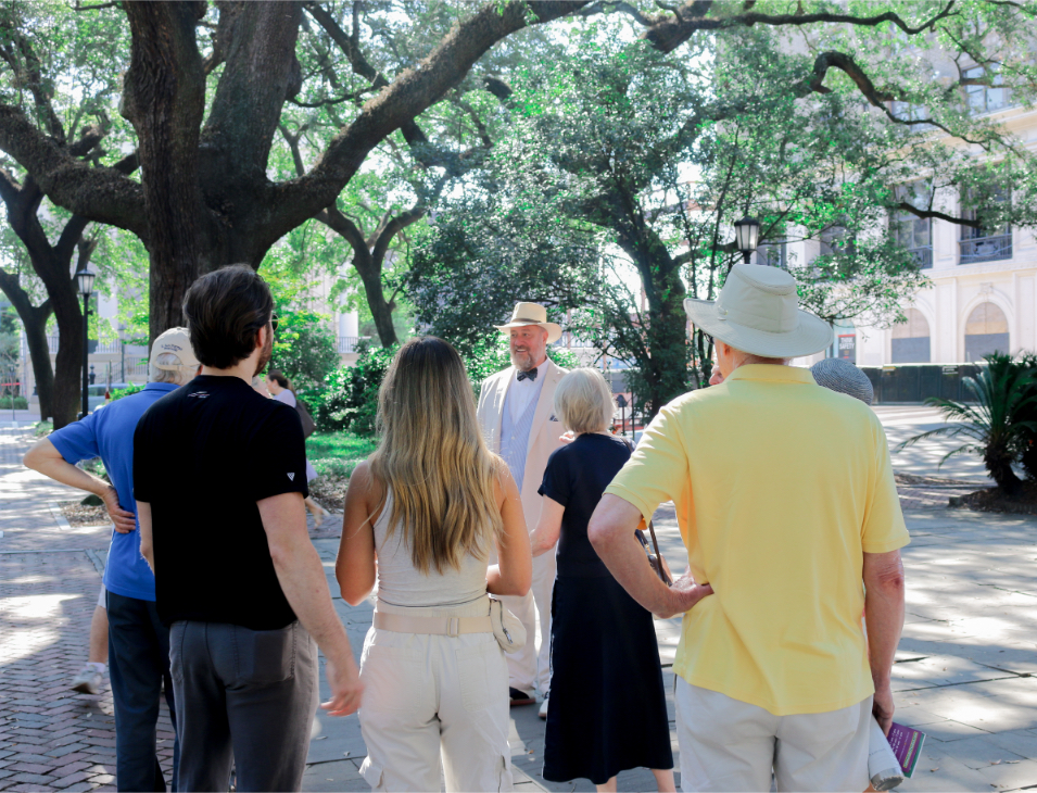 Group of tourists on a walking tour with guide in a park under large trees