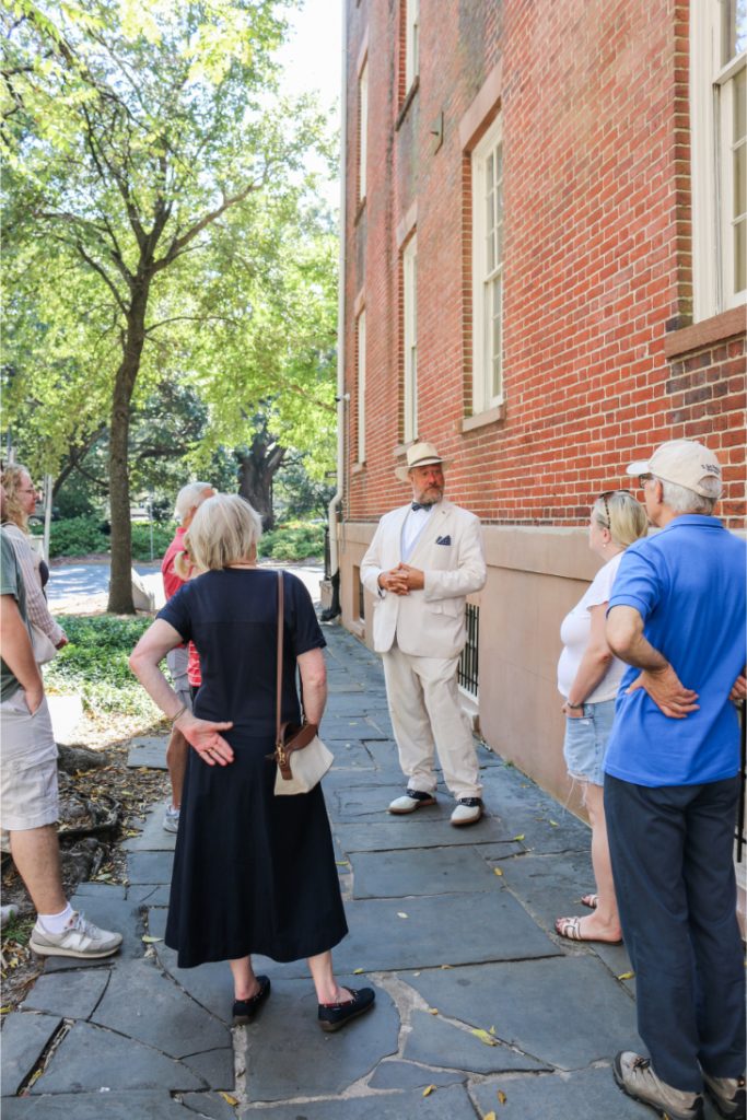 Group of tourists on a guided tour in front of a historic brick building on a sunny day