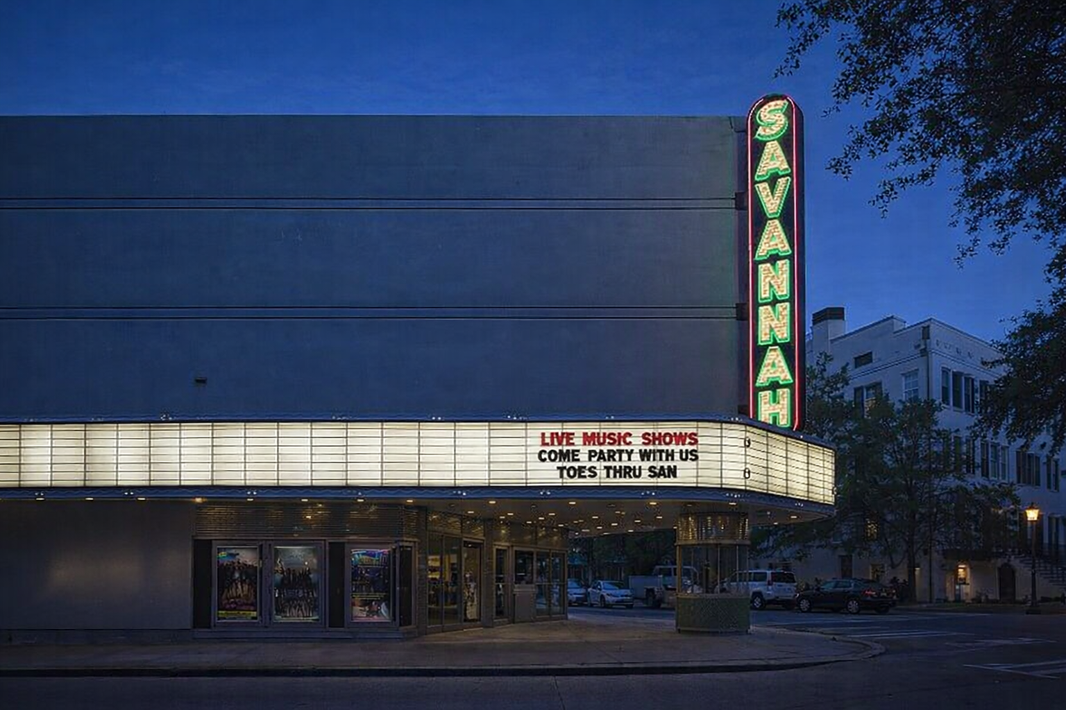 Neon-lit Savannah theater at dusk promoting live music shows and events on a vibrant city street corner