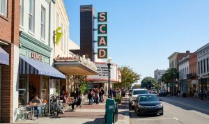 Street view with SCAD theater marquee, people dining outside Leopold's, and parked cars in a historic district
